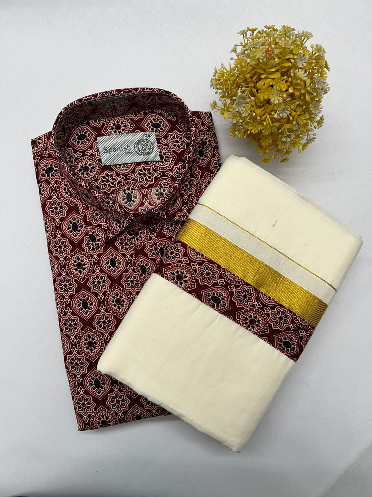 Folded patterned shirt with a folded white fabric and yellow band on a light gray background.