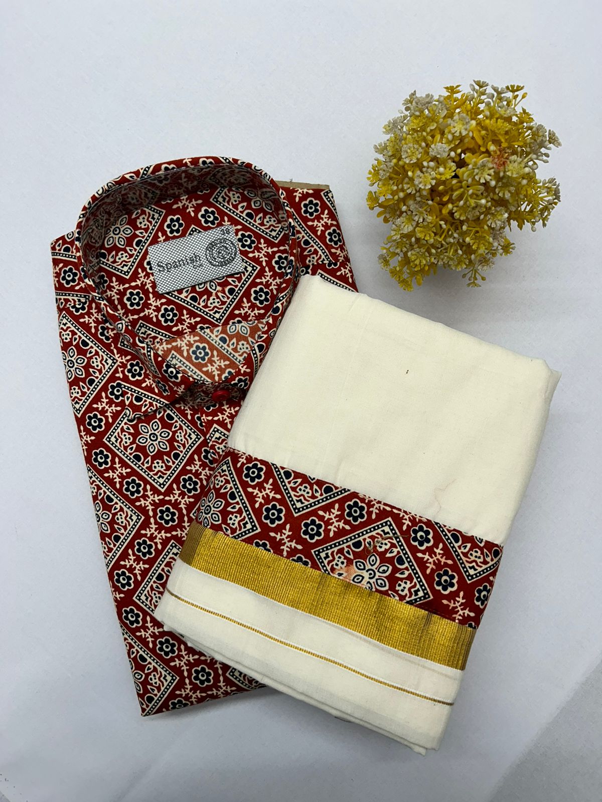 Folded red and white patterned fabric with a yellow flower on a white background