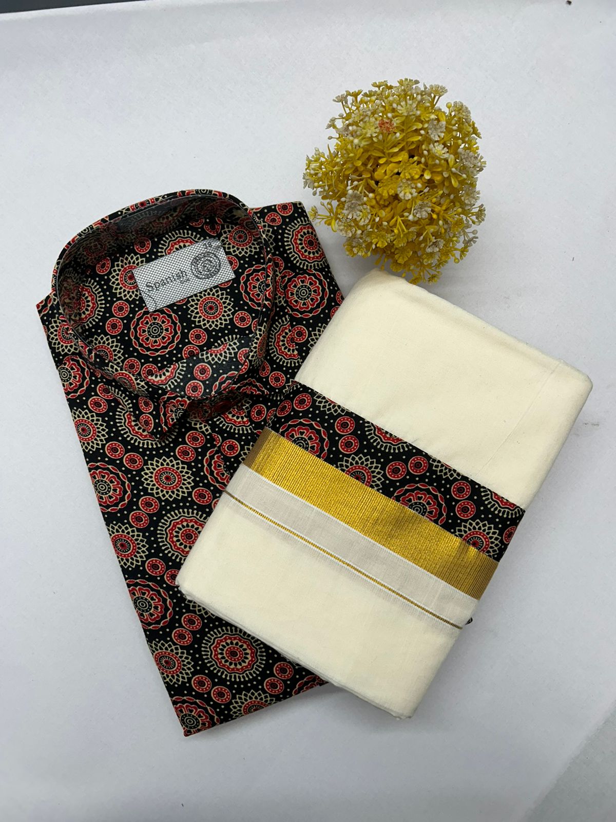 Folded patterned shirt with a white saree and yellow flowers on a white background