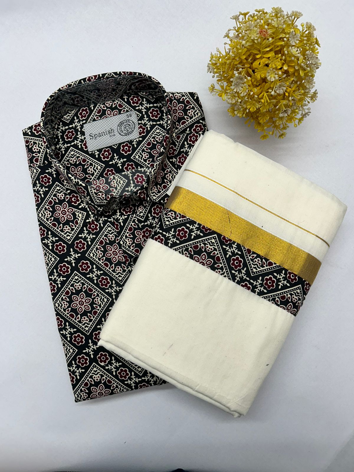Black patterned shirt with white pants and yellow trim on a white background