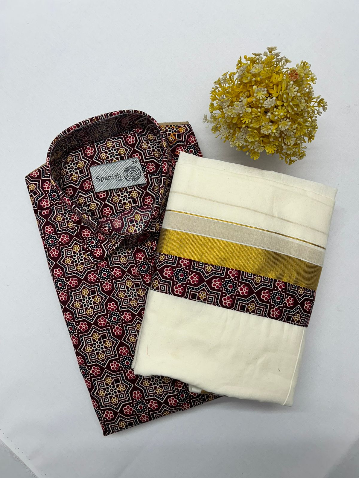 Traditional Indian saree with a patterned blouse and white saree with gold border on a light gray background.