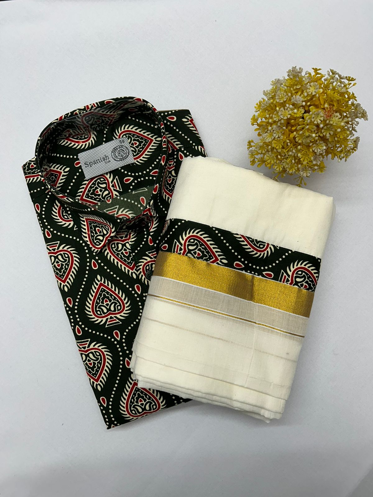 Black patterned fabric and white saree with gold border on a white background