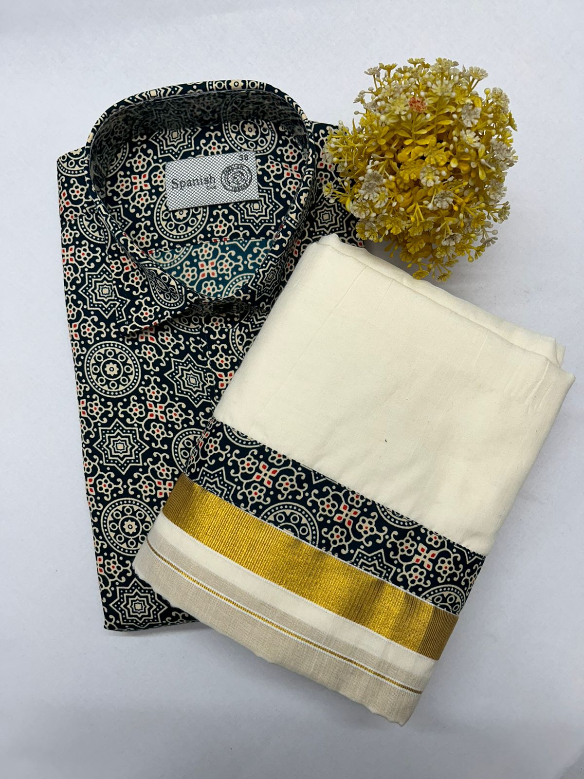 Black patterned saree with gold border and white blouse on a light gray background