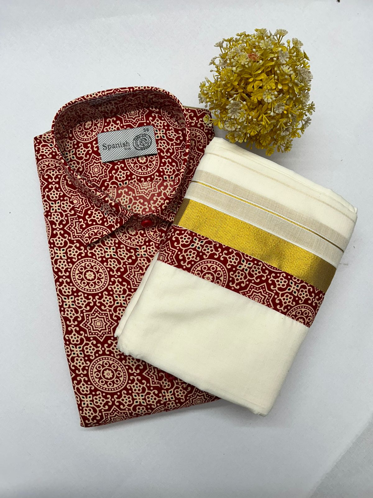 Folded patterned shirt with a white towel and decorative ball on a light gray background