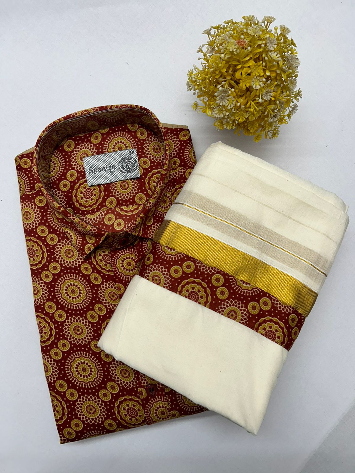 Folded patterned shirt with a folded fabric piece and decorative flower on a white background