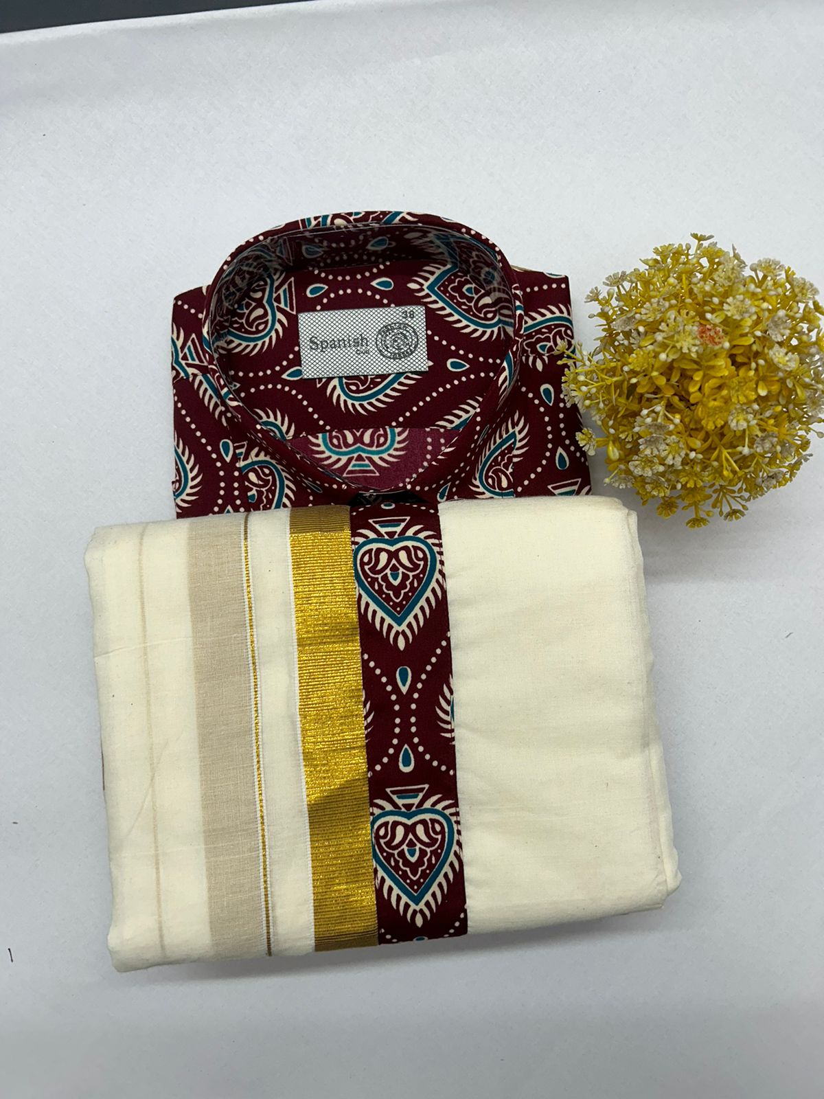 Maroon patterned shirt and cream fabric with yellow border on a white surface